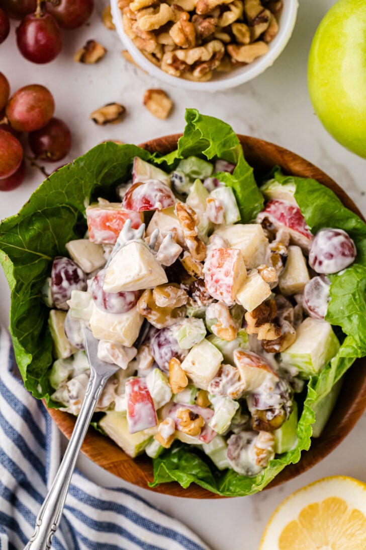 Waldorf Salad served on a bed of lettuce with a silver fork.