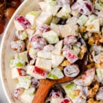 Waldorf salad 8 in white bowl with Greek key pattern, showing apples, celery, walnuts, and creamy dressing with wooden spoon