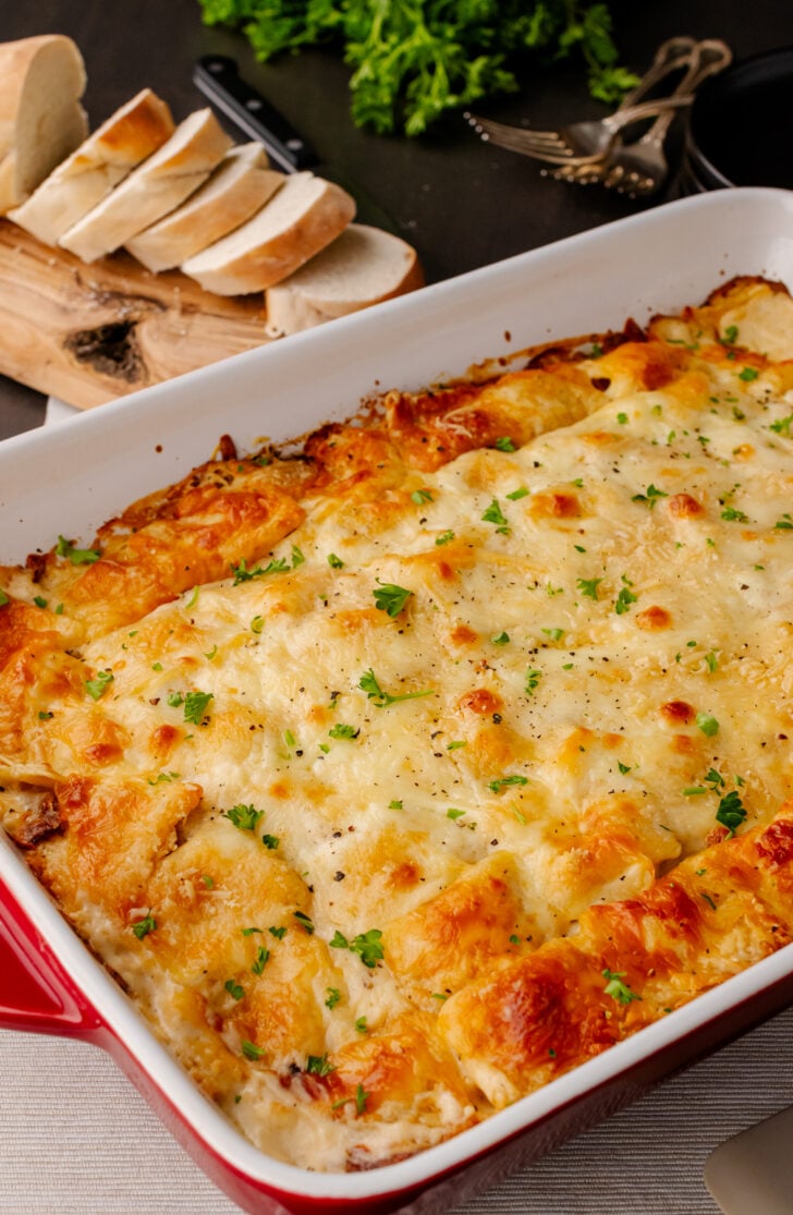 Baked Whie Ravoili Casserole in a red casserole dish served with bread.