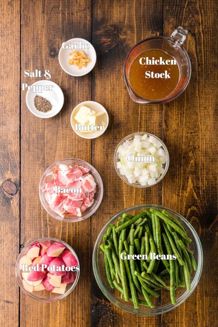 Green beans, potatoes, bacon and other ingredients in glass bowls.