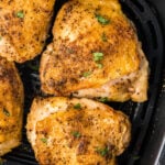 Air fryer chicken thighs in the basket of an air fryer.