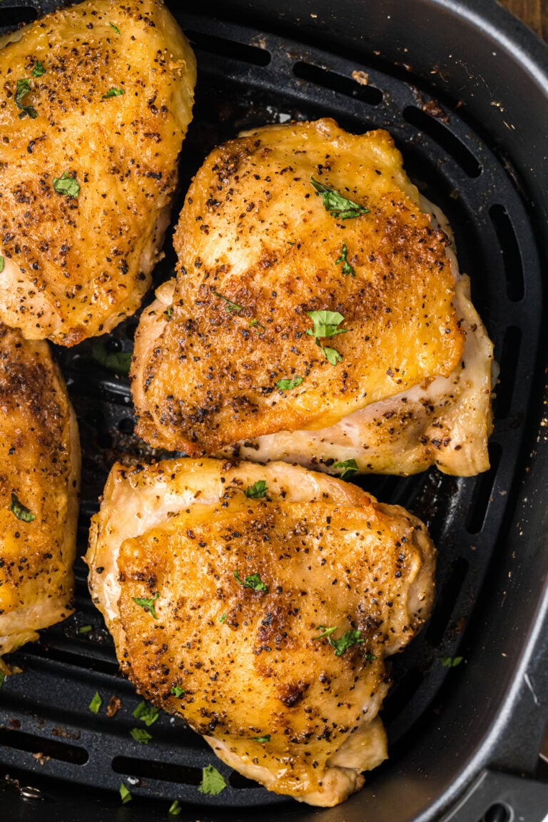 Air fryer chicken thighs in the basket of an air fryer.