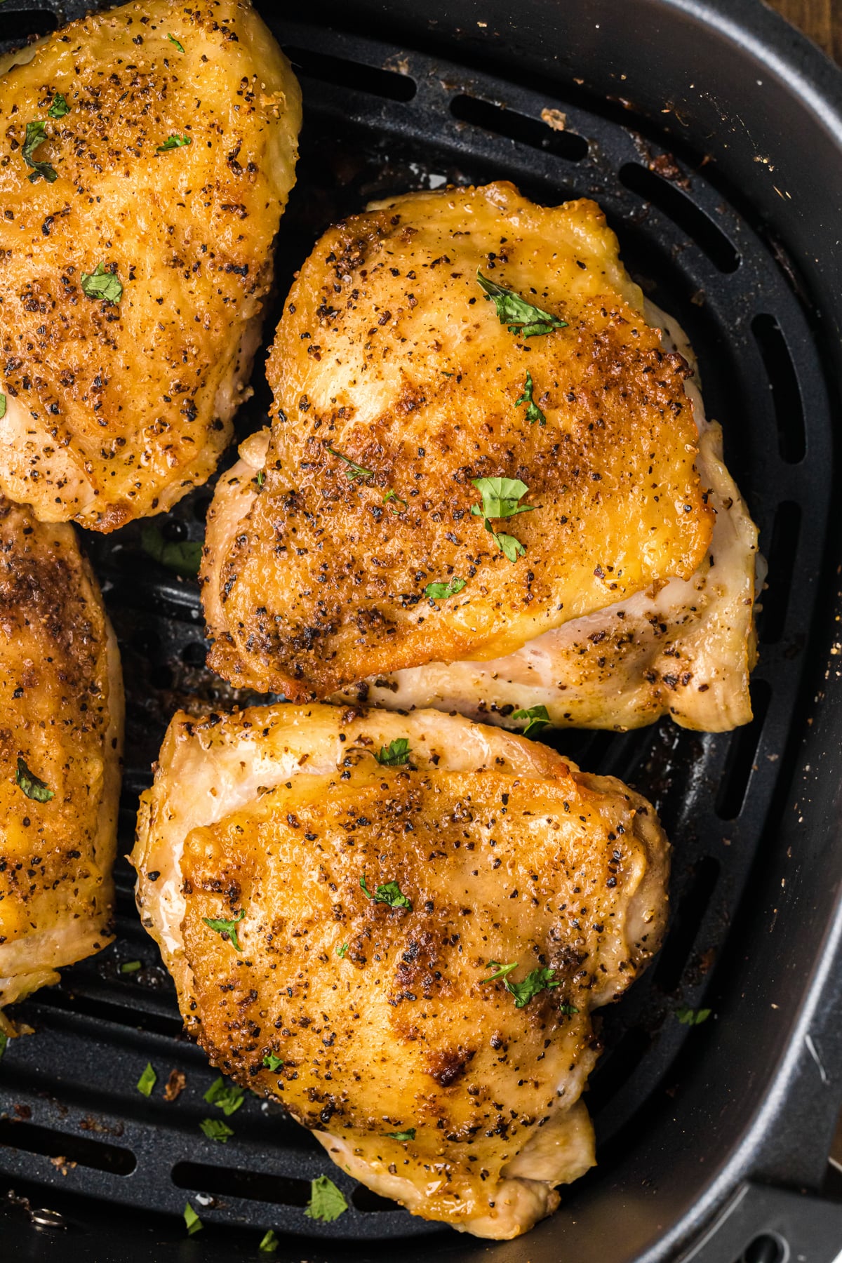 Air fryer chicken thighs in the basket of an air fryer.