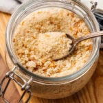 Brown butter breadcrumbs 9 1 in a glass jar with metal clasp lid and spoon on wooden surface