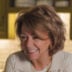 Headshot of a smiling woman with short, layered brown hair wearing a cream-colored top in a bright kitchen setting