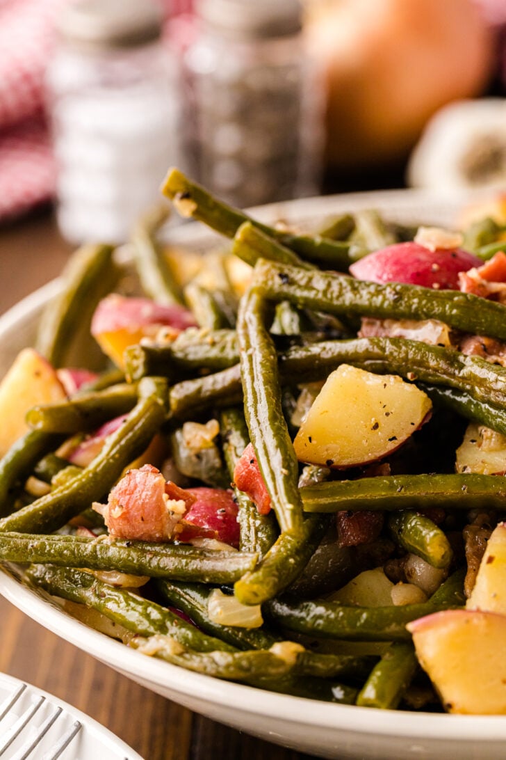 Green beans and potatoes with bacon served for dinner on a hite plate.