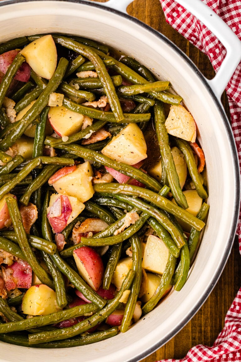 Southern Green Beans and Potatoes with bacon in a white bowl on a wooden table with red gingham cloth