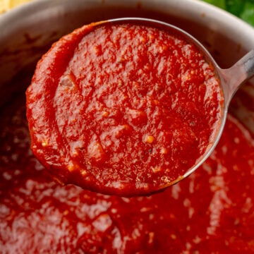 Homemade Marinara Sauce ladle dripping rich red tomato sauce into a pot, with fresh pasta and parsley visible nearby