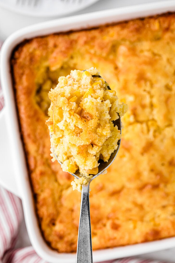Silver spoon with a spoonful of baked cornbread pudding.