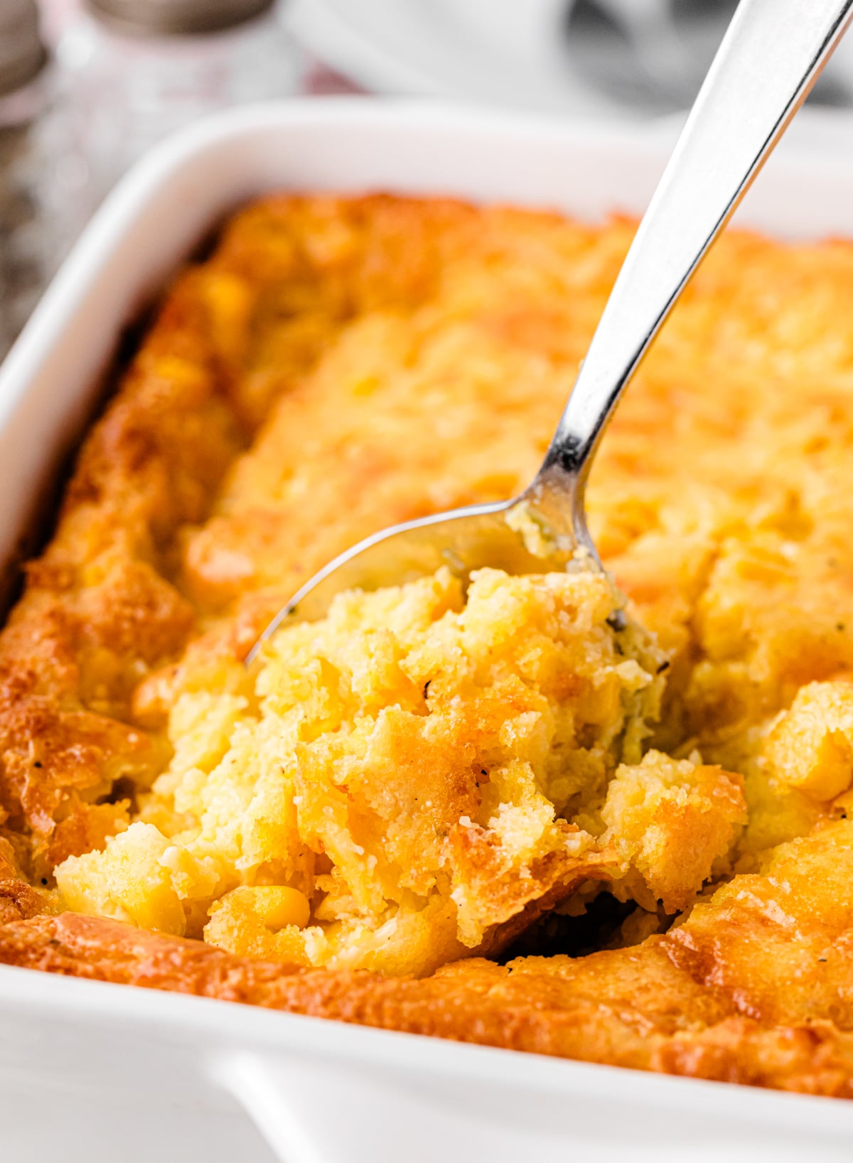 Cornbread pudding with cheese served with a spoon for the holidays.