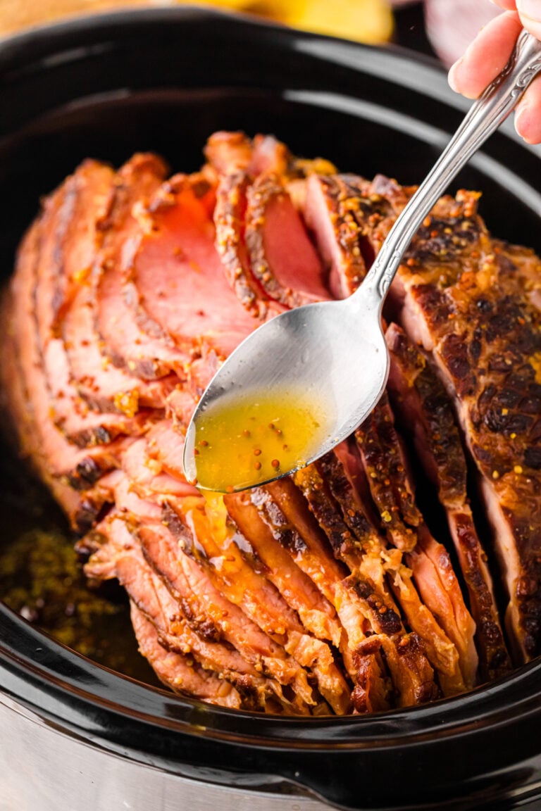 Crockpot ham 4 with glazed exterior being basted with golden honey butter sauce in slow cooker