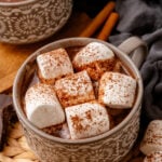 Easy Mexican Hot Chocolate mug topped with cinnamon-dusted marshmallows, served in decorative ceramic cup with cinnamon sticks and almonds