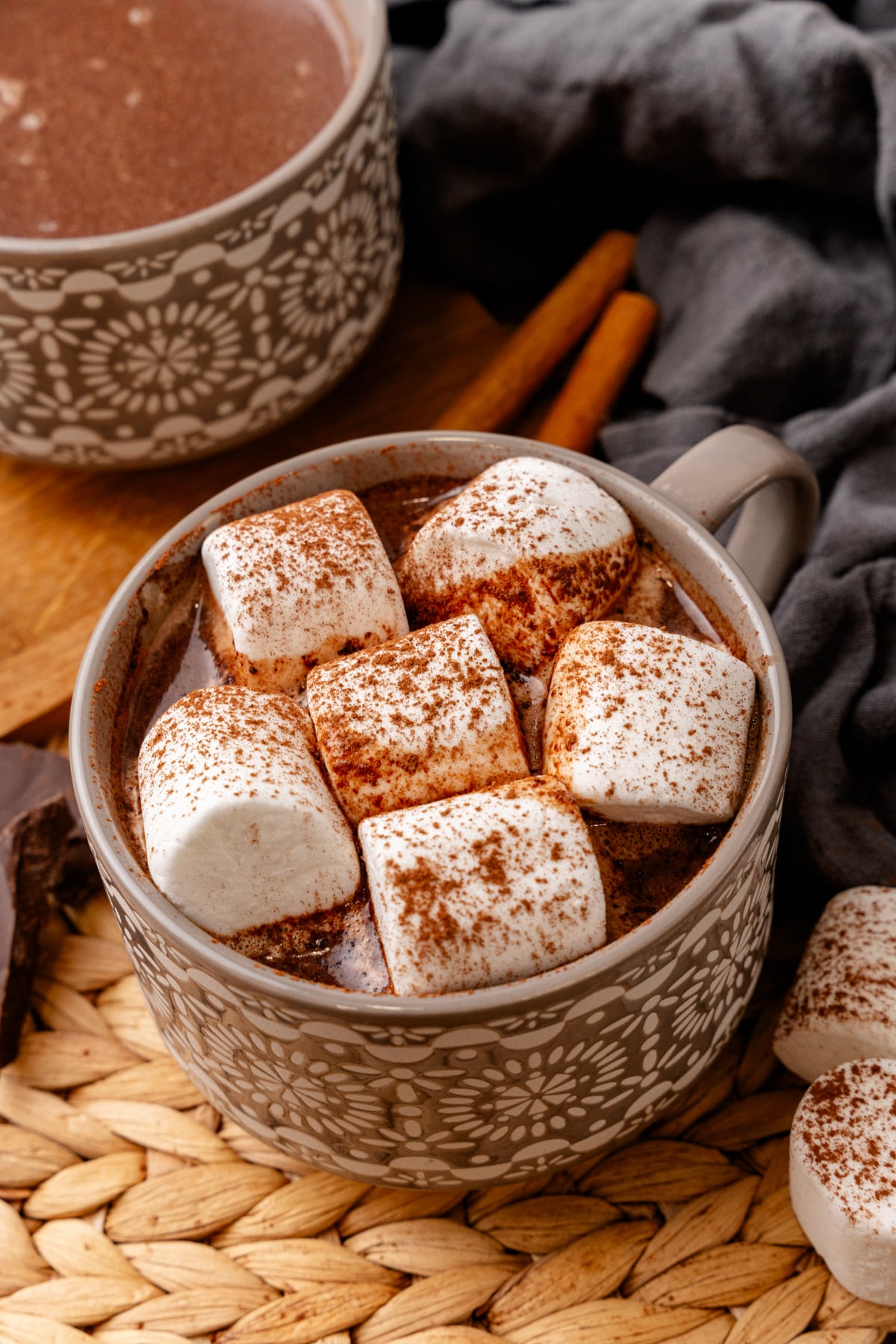 Easy Mexican Hot Chocolate mug topped with cinnamon-dusted marshmallows, served in decorative ceramic cup with cinnamon sticks and almonds