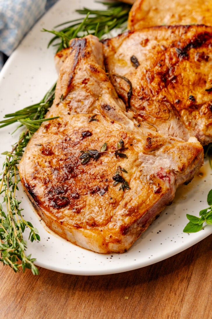 Best all-around meat marinade infused bone-in pork chops cooked and served on a white plate.