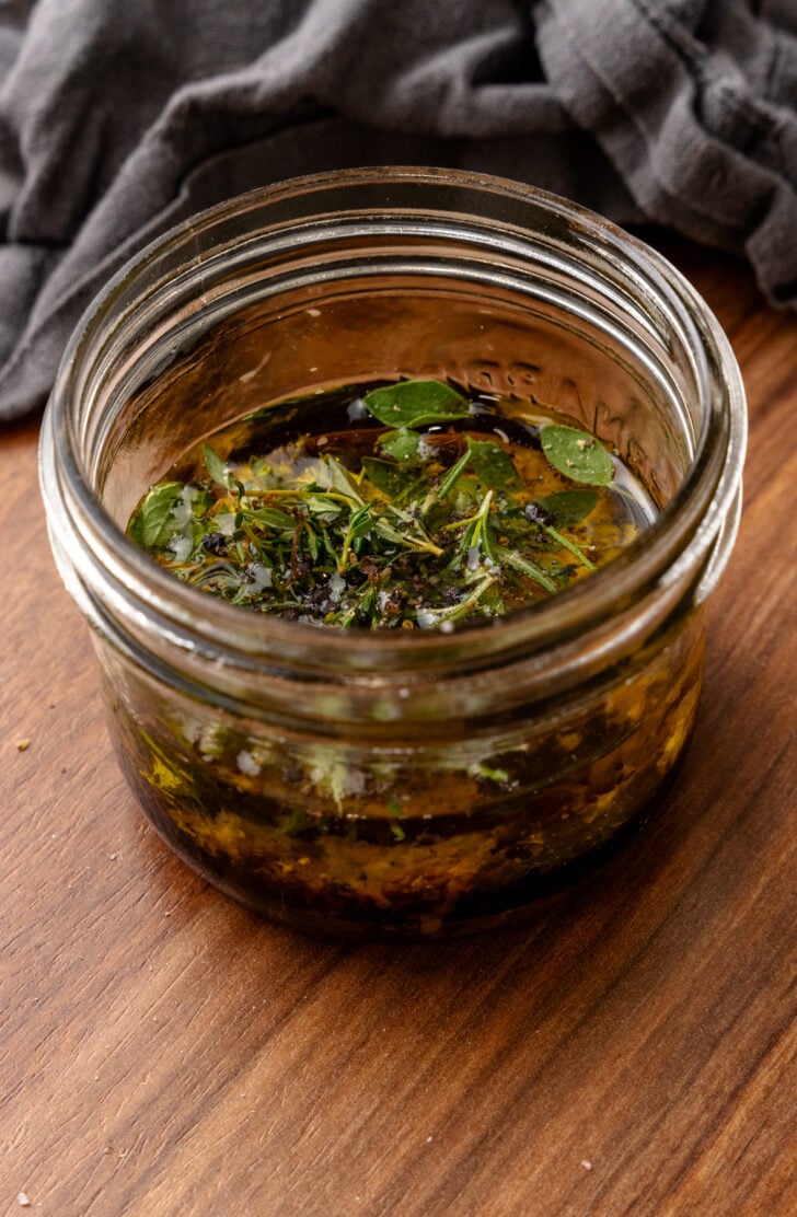 Fresh thyme and rosemary in a glass jar with oil and vinegar to make an all-purpose meat marinade.