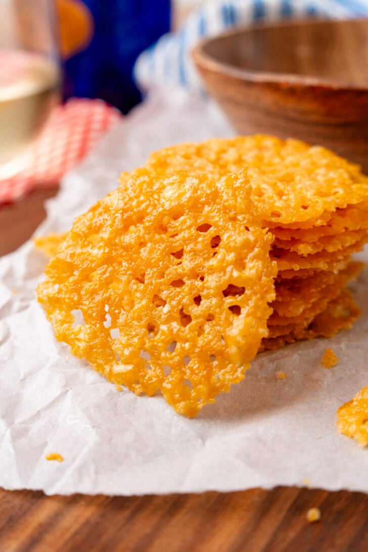 Parmesang cheese crisp crackers stacked on a parchment sheet for serving.
