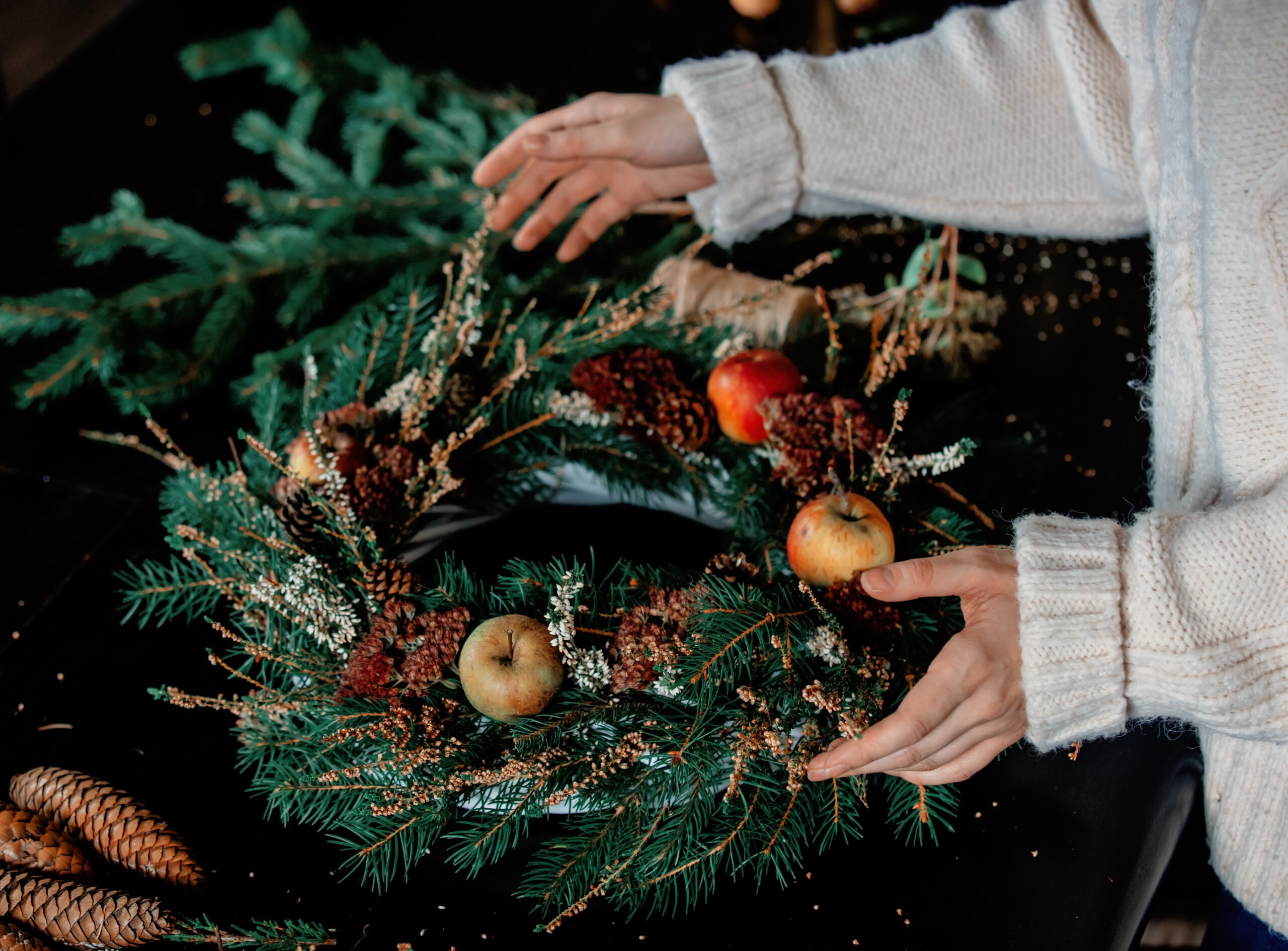 Child's hands arranging apples on evergreen wreath with berries and pinecones, 7 Smart Ways To Get Ready For The Holiday Season
