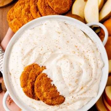 Eggnog dip 8 1 in white bowl with cinnamon sugar topping, served with gingersnap cookies and apple slices on wooden surface
