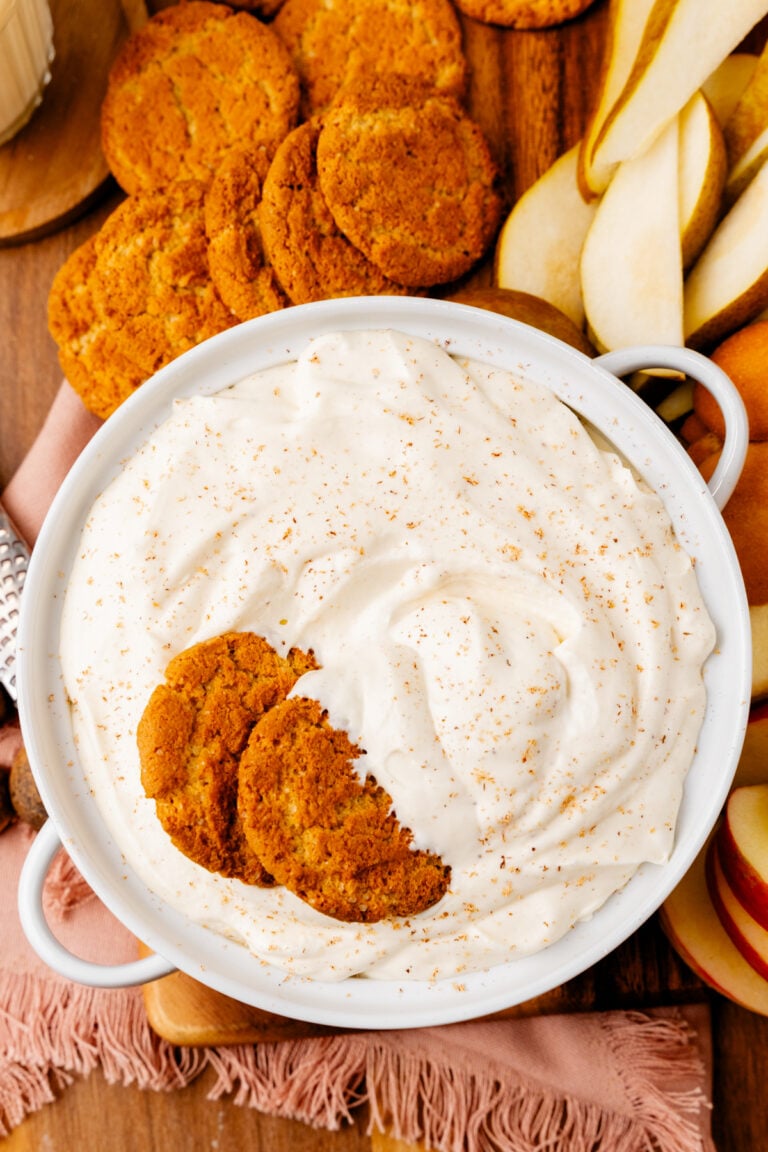 Eggnog dip 8 1 in white bowl with cinnamon sugar topping, served with gingersnap cookies and apple slices on wooden surface