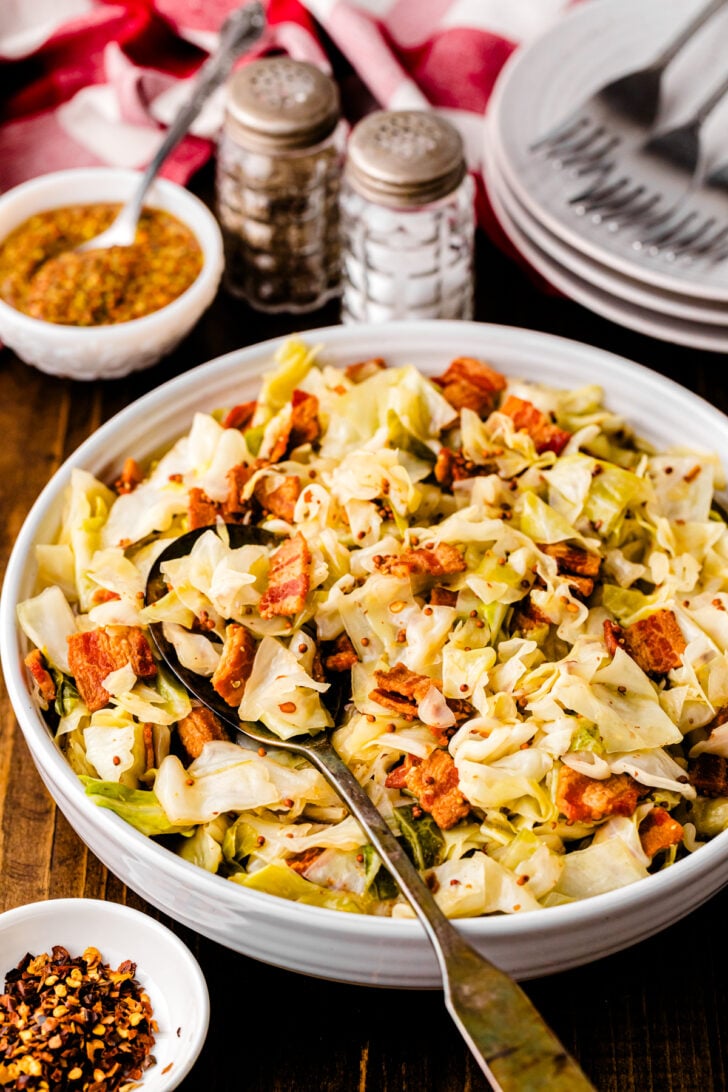 White bowl with Southern Fried Cabbage and Bacon sereved with a metal fork.