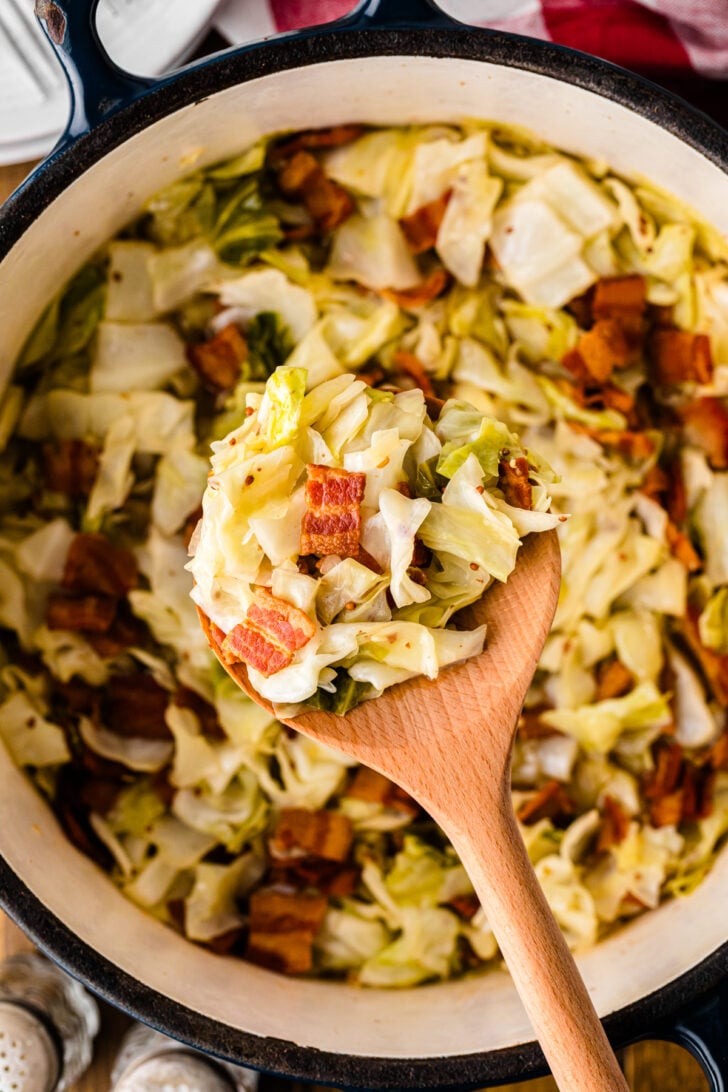Wooden spoon with serving of Southern Fried Cabbage And Bacon.