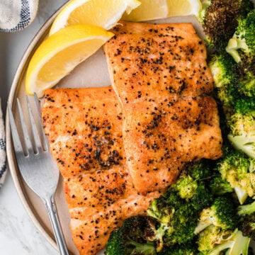 Plated airfryer salmon 10 e1755524148211 with crispy blackened seasoning, roasted broccoli, and lemon wedges on ceramic dish with fork