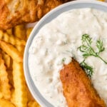 Crispy fried fish and golden french fries with Easy Homemade Tarter Sauce in white bowl, garnished with fresh dill