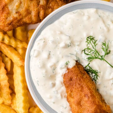 Crispy fried fish and golden french fries with Easy Homemade Tarter Sauce in white bowl, garnished with fresh dill