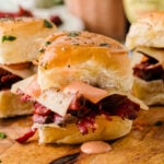 Reuben sliders arranged on a baking sheet before going in the oven, topped with butter and everything seasoning.