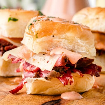 Featured image of golden baked Reuben sliders with melted Swiss cheese and sauerkraut on Hawaiian rolls.