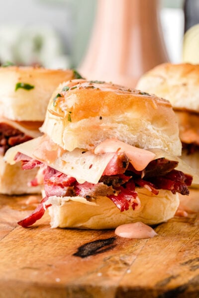 Featured image of golden baked Reuben sliders with melted Swiss cheese and sauerkraut on Hawaiian rolls.