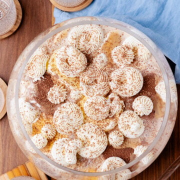Southern Coffee Punch dessert in clear bowl topped with whipped cream piped rosettes and cinnamon, served with glasses on wooden table