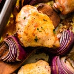 Baked Ranch Chicken – Sheet Pan Recipe with golden chicken breasts and purple onion wedges on a sheet pan, garnished with black pepper and f