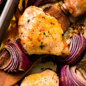 Baked Ranch Chicken – Sheet Pan Recipe with golden chicken breasts and purple onion wedges on a sheet pan, garnished with black pepper and f