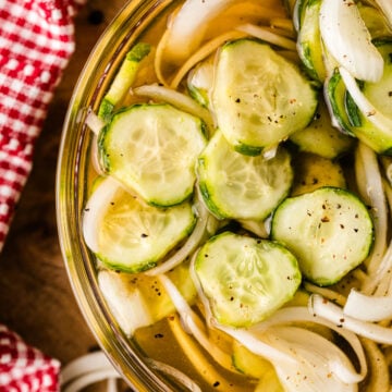 Homemade refrigerator pickles 7 with sliced cucumbers and onions in a glass jar with brine and black pepper