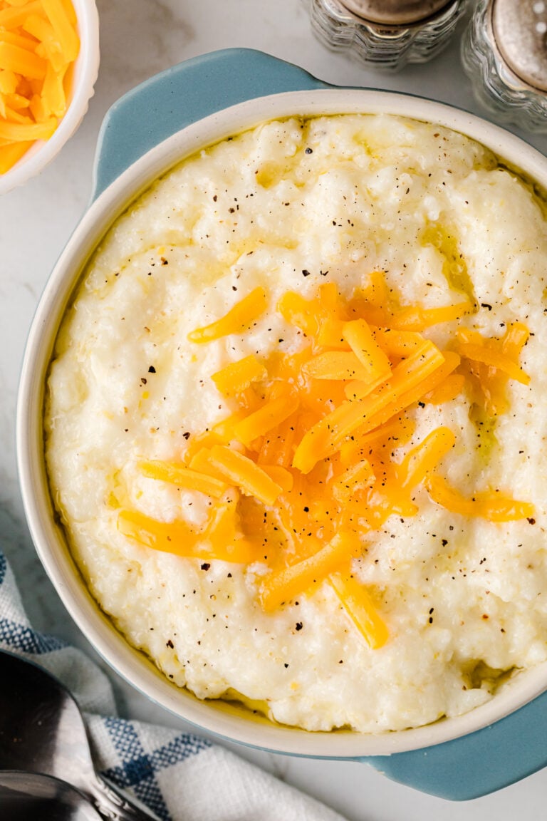 Slow Cooker Cheese Grits topped with sautéed yellow peppers and black pepper in a blue and white bowl