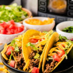 Close-up of slow cooker taco meat with rich seasoning in a black crock pot.