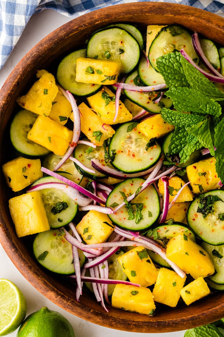 Pineapple Cucumber Salad in wooden bowl with yellow pineapple chunks, green cucumber slices, red onion, fresh mint, and chili flakes