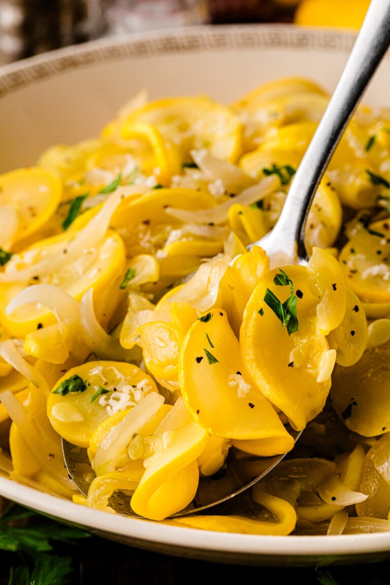 Creamed squash and onions 10 in a white bowl with fresh parsley and black pepper garnish, served with a silver spoon