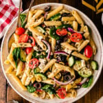Mediterranean pasta salad 5 with penne, tomatoes, cucumbers, olives, and feta cheese in a decorative white bowl on dark wood