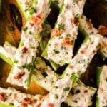 Stuffed celery 5 with creamy filling, crispy bacon bits, and green onions on a wooden surface