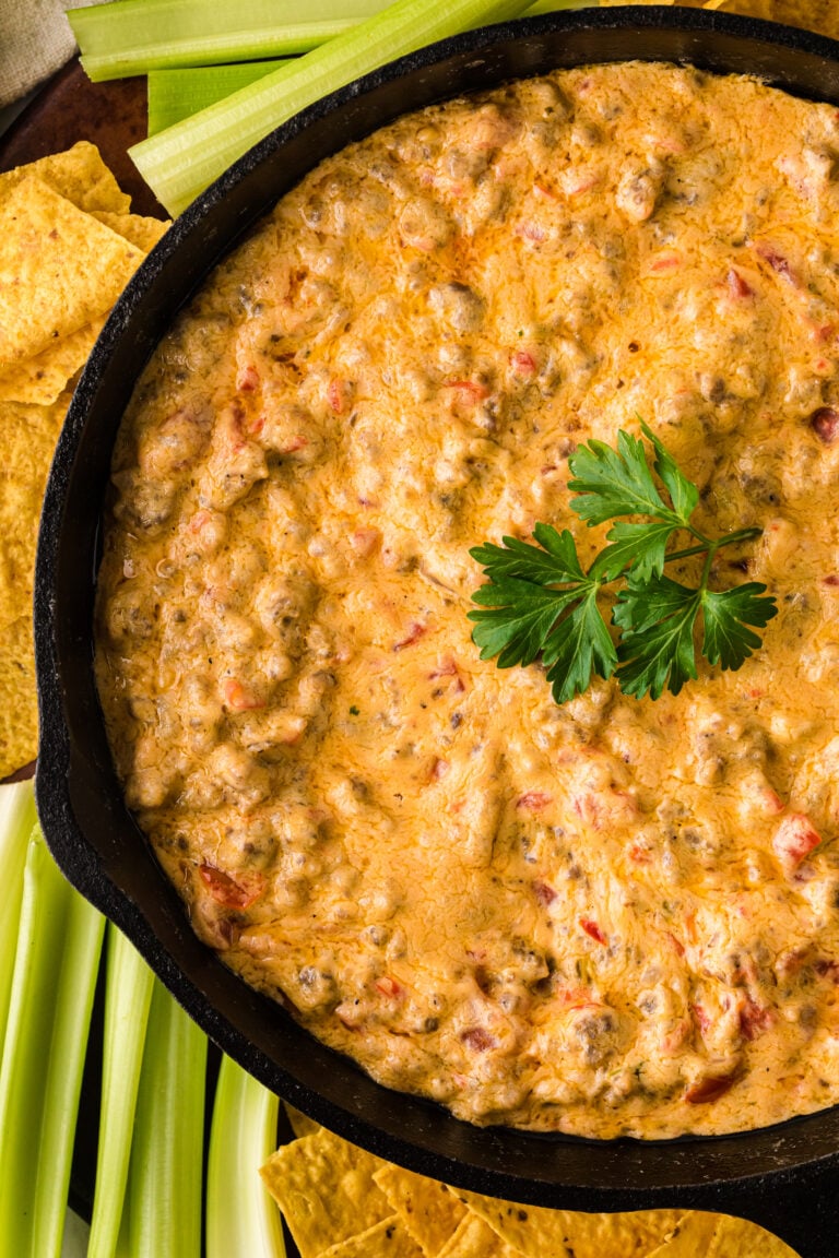 Pimento Cheese and Sausage Dip 5 in black cast iron skillet with tortilla chips and celery sticks on the side, garnished with fresh parsley
