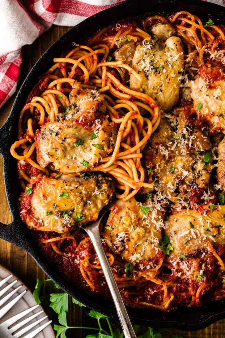 Fully cooked skillet chicken spaghetti in a cast iron skillet, with tender chicken and spaghetti in rich tomato sauce topped with melted Parmesan for a one-pan dinner.