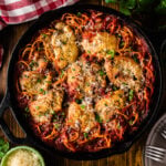 Skillet chicken spaghetti in a cast iron pan with creamy cheese sauce and diced tomatoes.