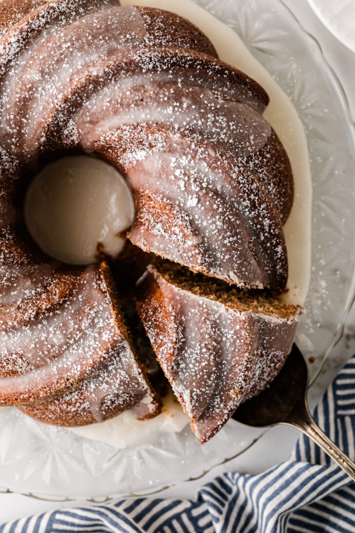 Overhead view of sliced spice cake 9 dusted with powdered sugar on a decorative white plate with blue-striped napkin