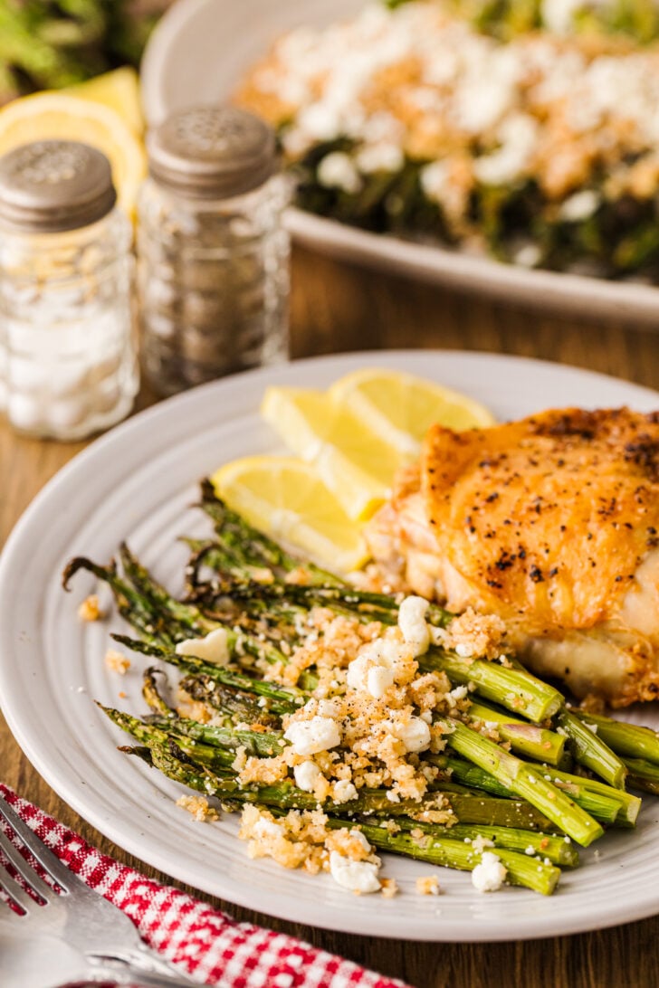 Roasted asparagus with lemon panko and feta on a white plate served alongside roasted chicken for an easy spring dinner.