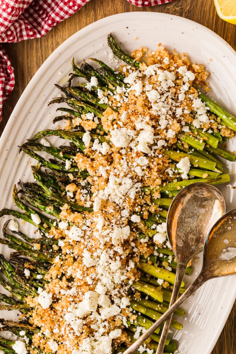 Oven roasted asparagus spears topped with crumbled feta cheese on a serving platter