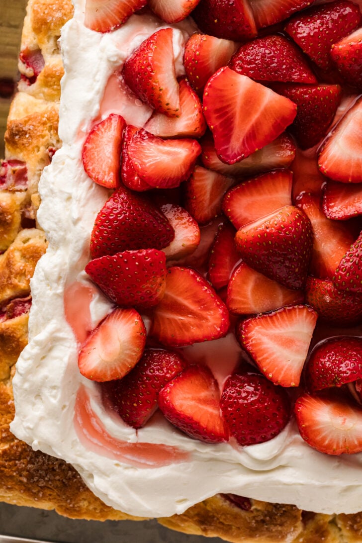 Strawberry Shortcake Sheet Cake topped with fresh sliced strawberries and whipped cream frosting on a golden cake layer, overhead view