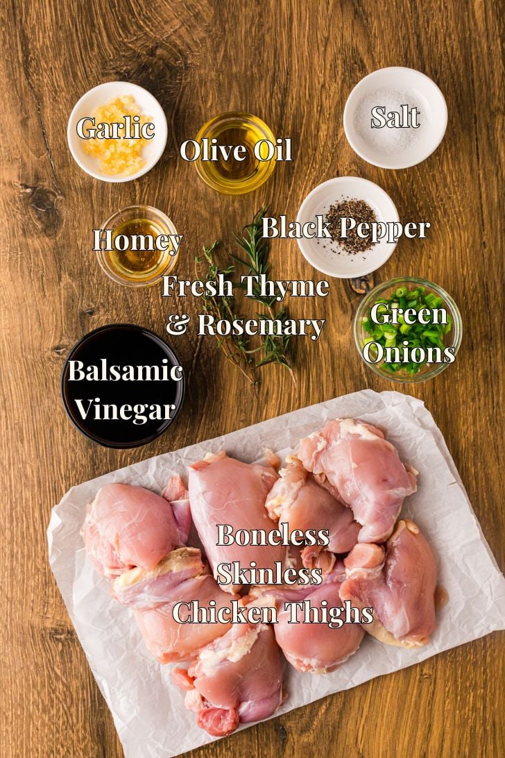 Honey marinade chicken thighs ready for soaking in glossy dark balsamic with fresh thyme and rosemary with garlic and honey.