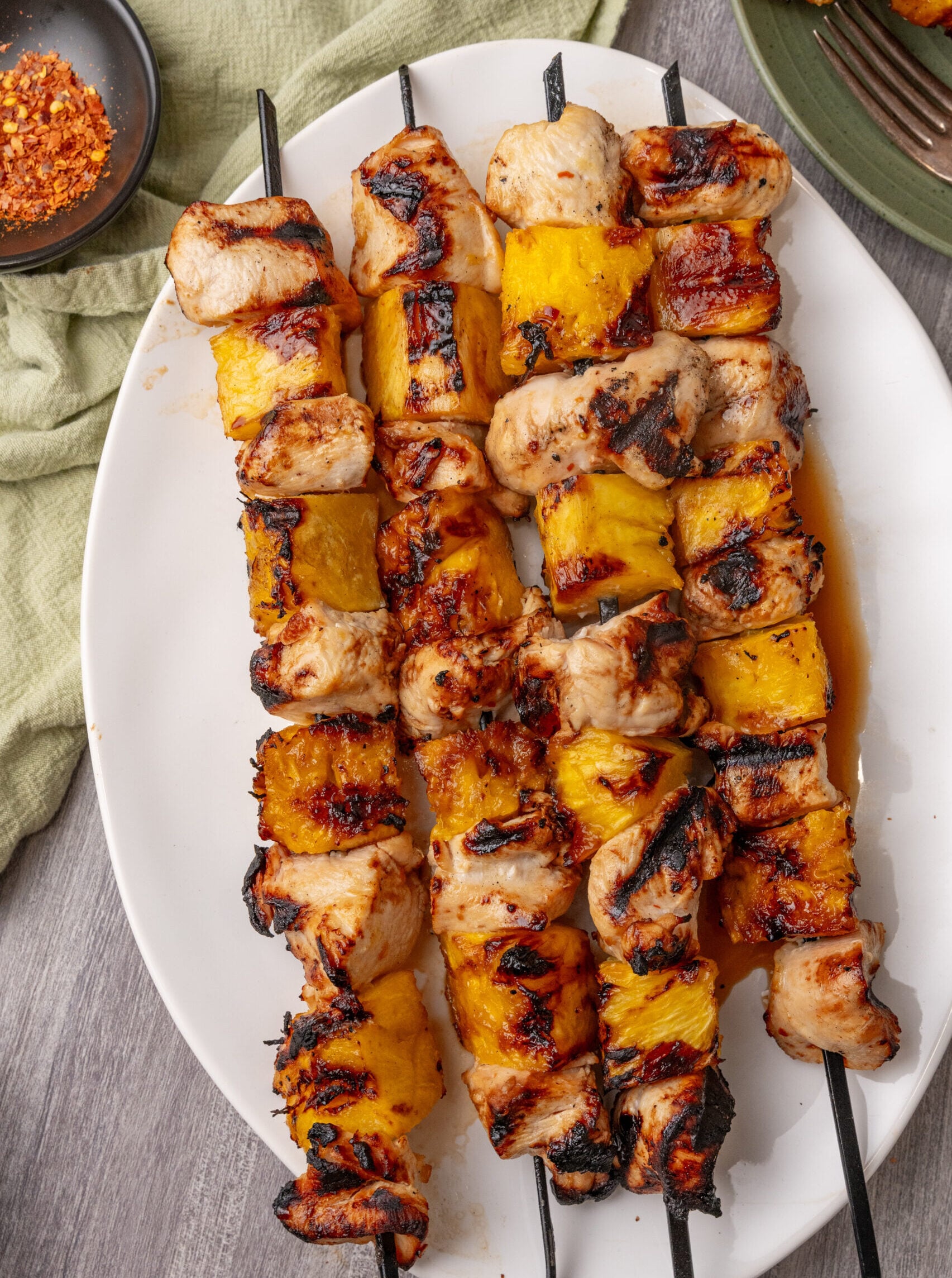 Grilled Hawaiian chicken and pineapple skewers on a white plate.
